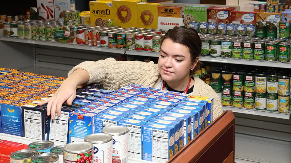 Student volunteer stocking shelves in the Basic Needs Center